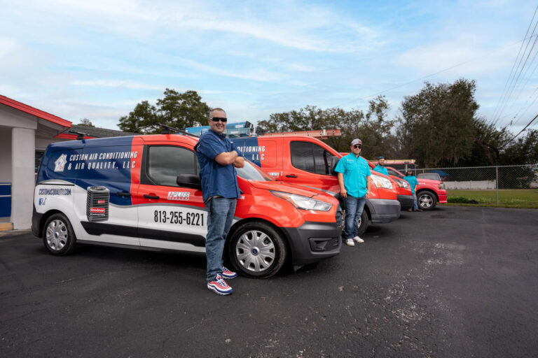 Custom Air Conditioning Air Quality team members stand proudly beside their branded service vans parked outside the companys office ready for AC repair and service calls 768x512 1