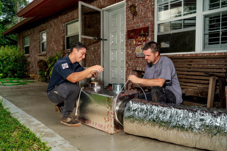 Two Custom Air Conditioning Air Quality technicians work on sealing an insulated air duct with metallic tape 768x512 1